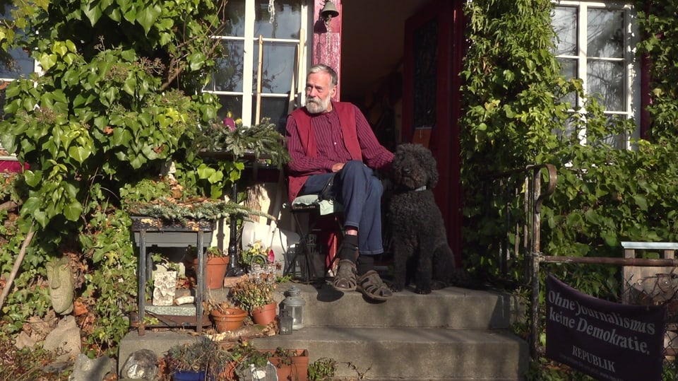 Robert Widmer-Demuth sitzt gemütlich neben seinem Hund auf der Treppe vor dem Haus.