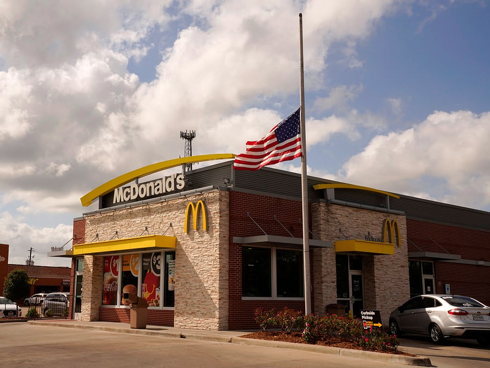 US-Fahne auf Halbmast, McDonalds-Filiale im Hintergrund.