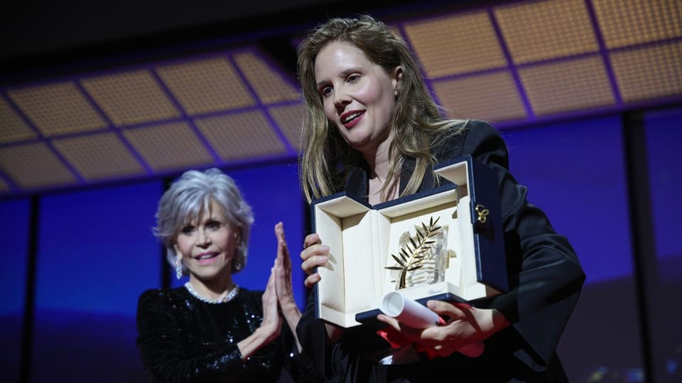 Justine Triet mit der Goldenen Palme, im Hintergrund steht Jane Fonda.