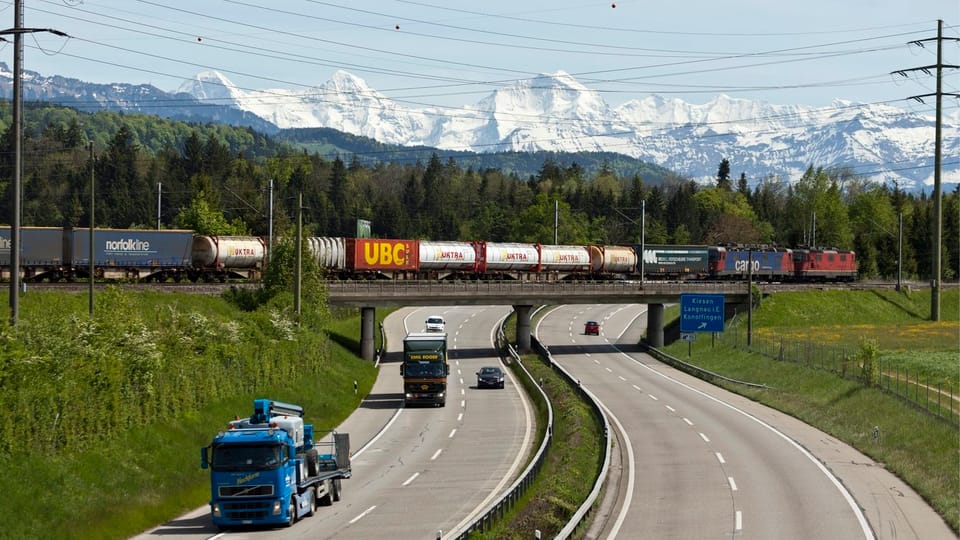 Ein Güterzug fährt über eine Autobahnbrücke.