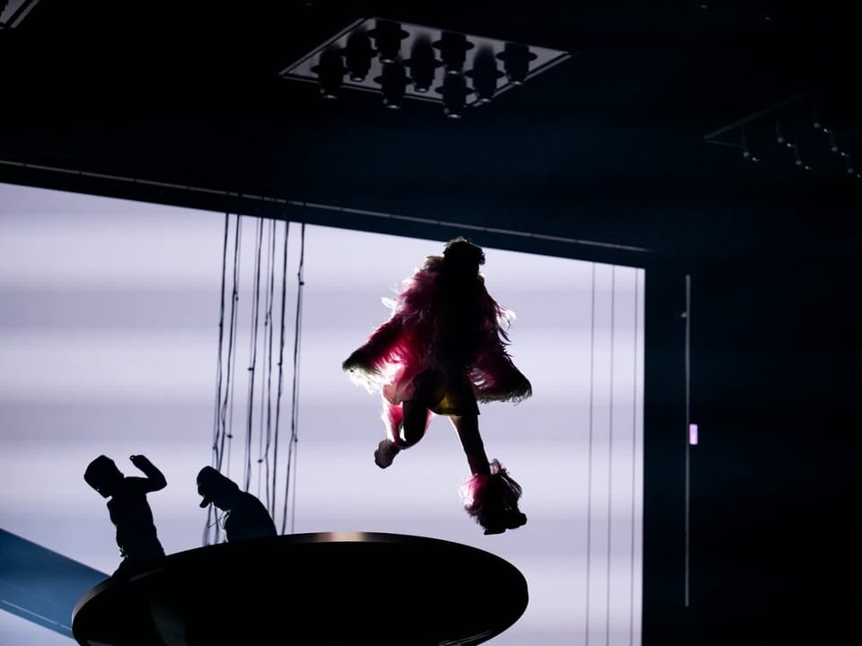 Künstlerin schwebt während einer Bühnenaufführung an Seilen über der Bühne.