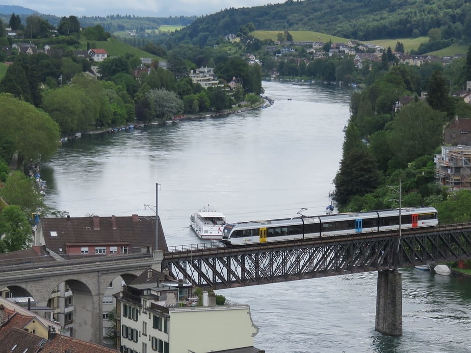 Ein Zug fährt über eine Brücke am Rhein.
