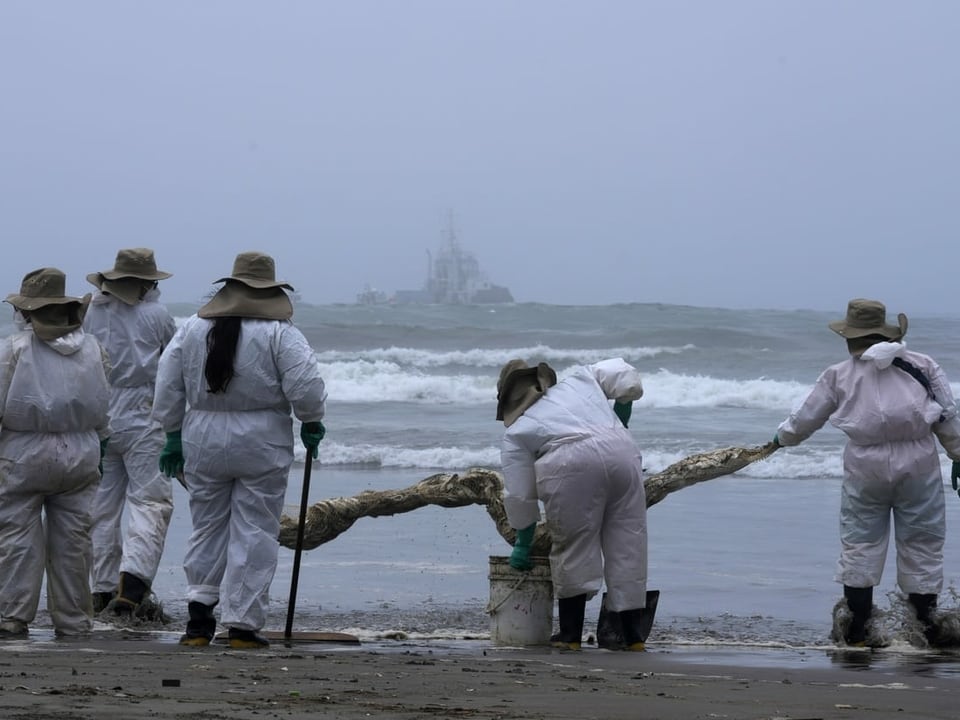 Einsatzkräfte beteiligen sich nach dem Ölunfall an einer Säuberungsaktion am Cavero-Strand im Distrikt Ventanilla.