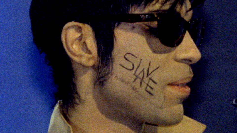 Prince mit Sonnenbrille und dem Wort «Slave» in schwarzen Lettern auf seiner rechten Wange.