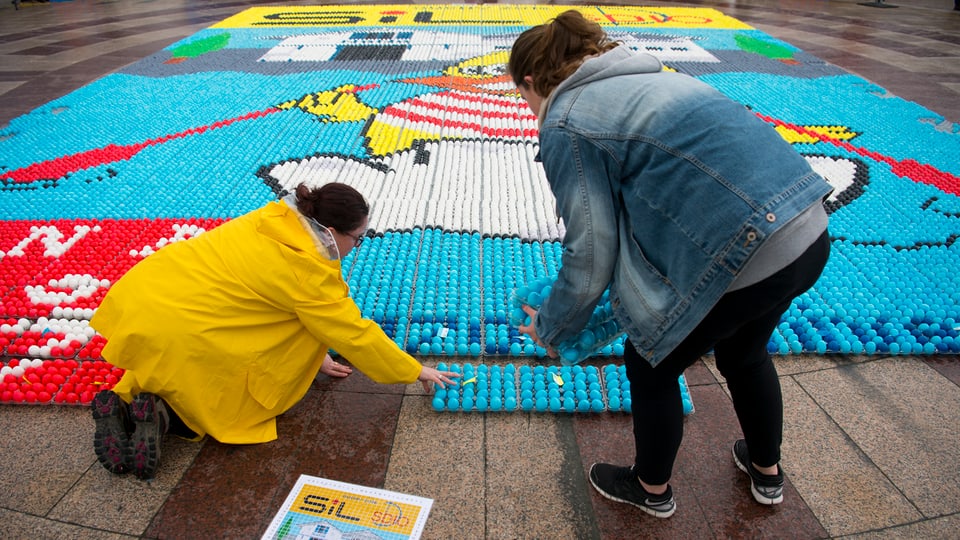 Zwei Frauen komplettieren ein Mosaik aus Ostereiern.