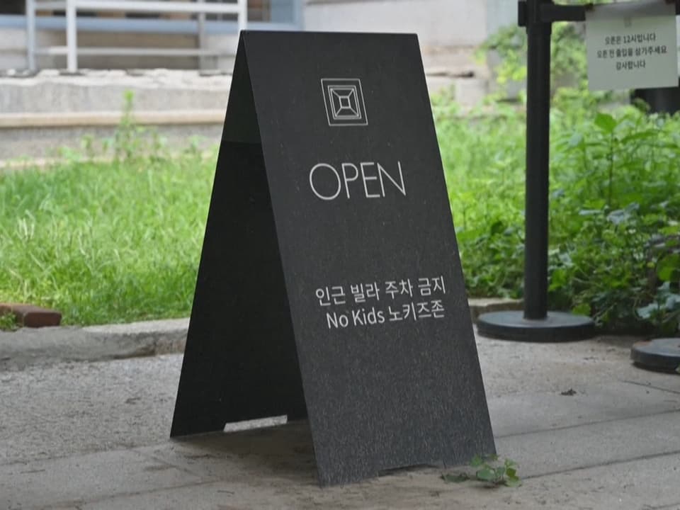 Schwarzes Schild mit 'OPEN', zusätzlichen koreanischen Texten und 'No Kids' draussen.