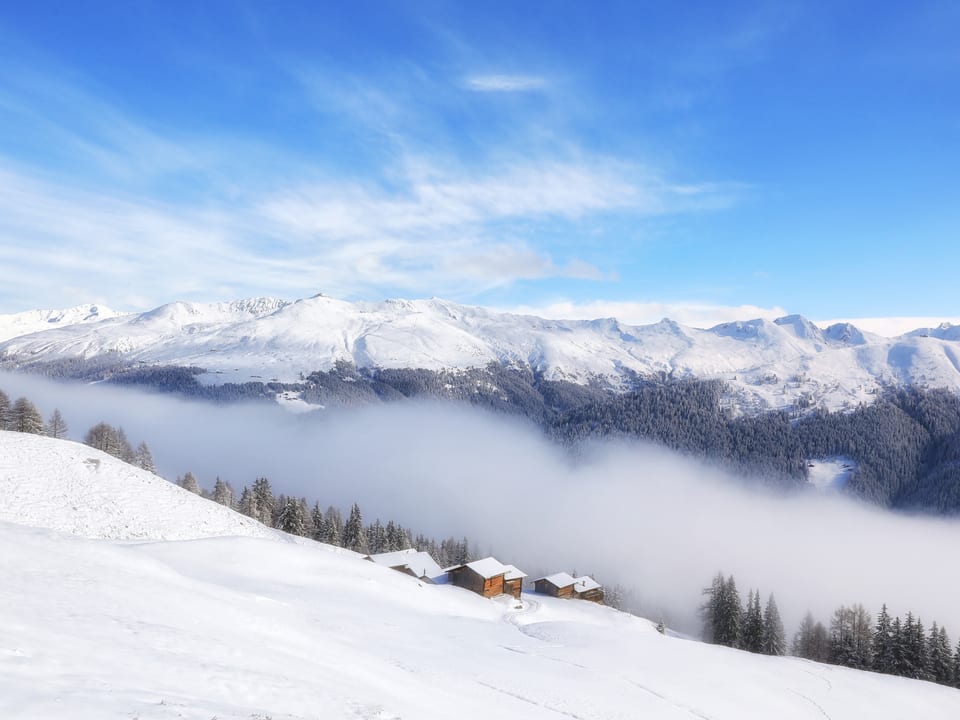 Winterlandschaft bei blauem Himmel, unten im Tal liegt Nebel.