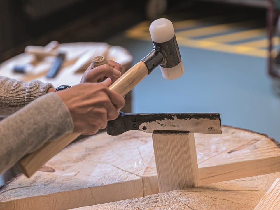 Ein Foto einer Person, die mit Holz arbeitet: In der Schindelwerkstatt legt das Publikum selber Hand an.
