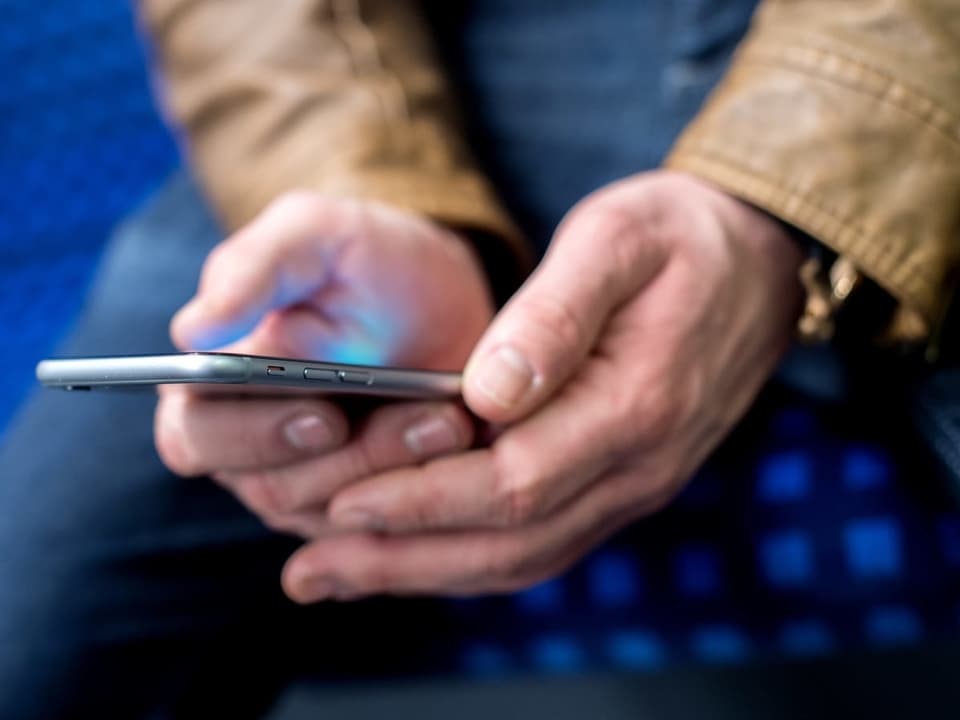 Neun von zehn Menschen in der Schweiz besitzen ein Smartphone Ein Smartphone liegt in zwei Händen. Nahaufnahme.