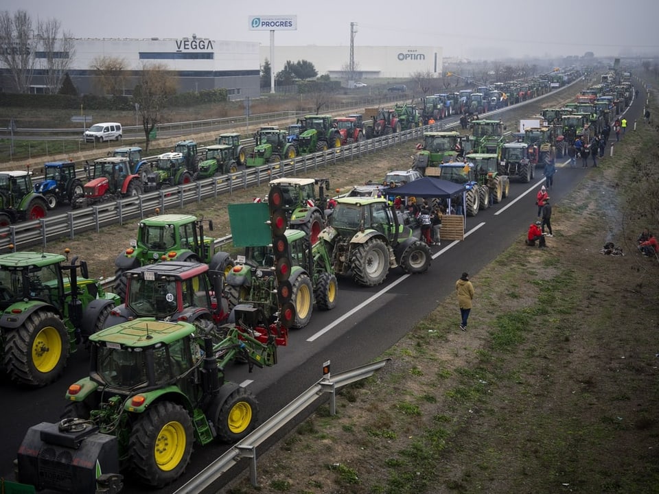 Auf einer Autobahn stehen Dutzende von Traktoren. 