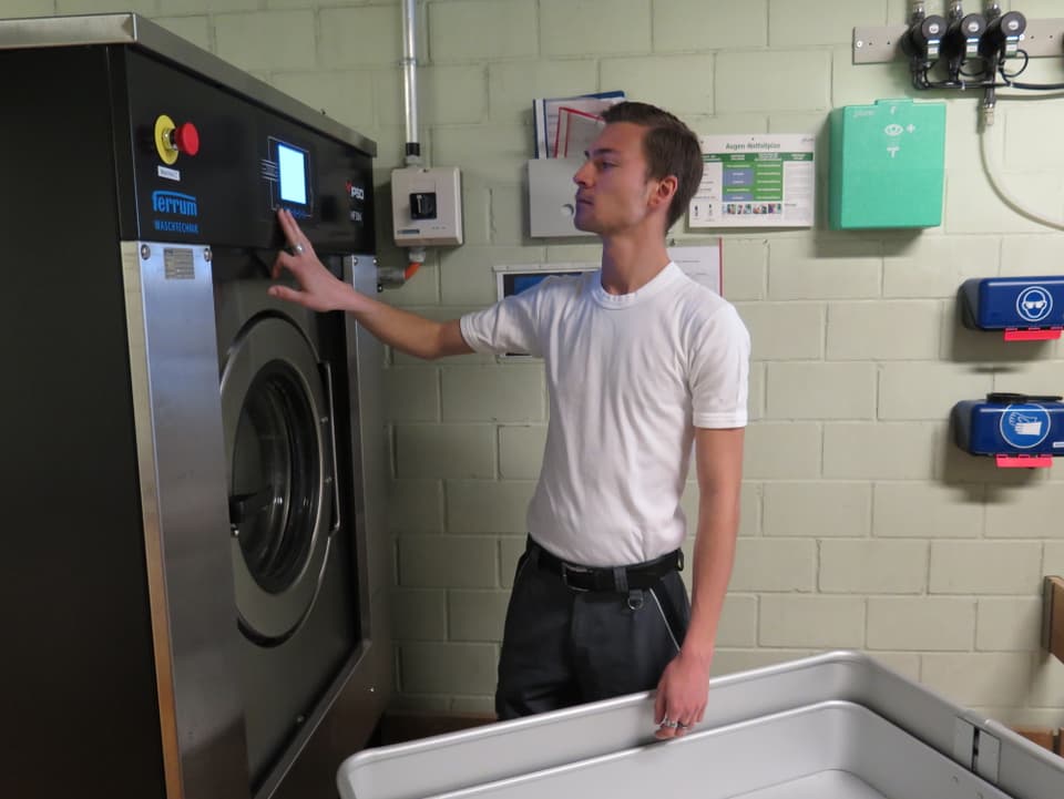 Mann bedient Waschmaschine.