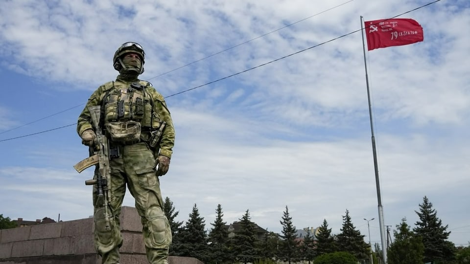 Ein russischer Soldat in Cherson, aufgenommen am 20. Mai 2022. Im Hintergrund die Replik einer russischen Siegesflagge