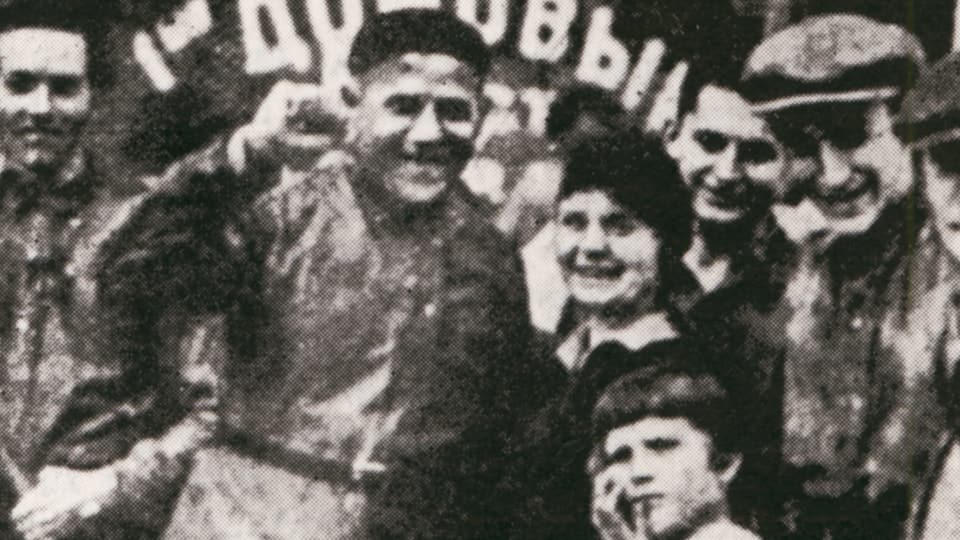 Alte Fotografie zeigt einen Mann mit erhobener Faust in einer Gruppe Menschen.