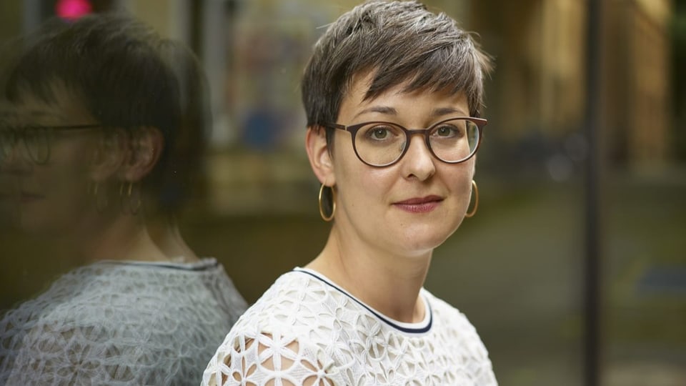 Frau mit kurzen, braunen Haaren und runder Brille