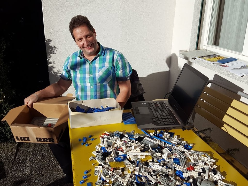 Das Bild zeigt einen Mann im Garten mit vielen Legosteinchen. 