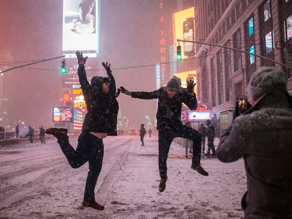 Männer springen am Times Square herum.