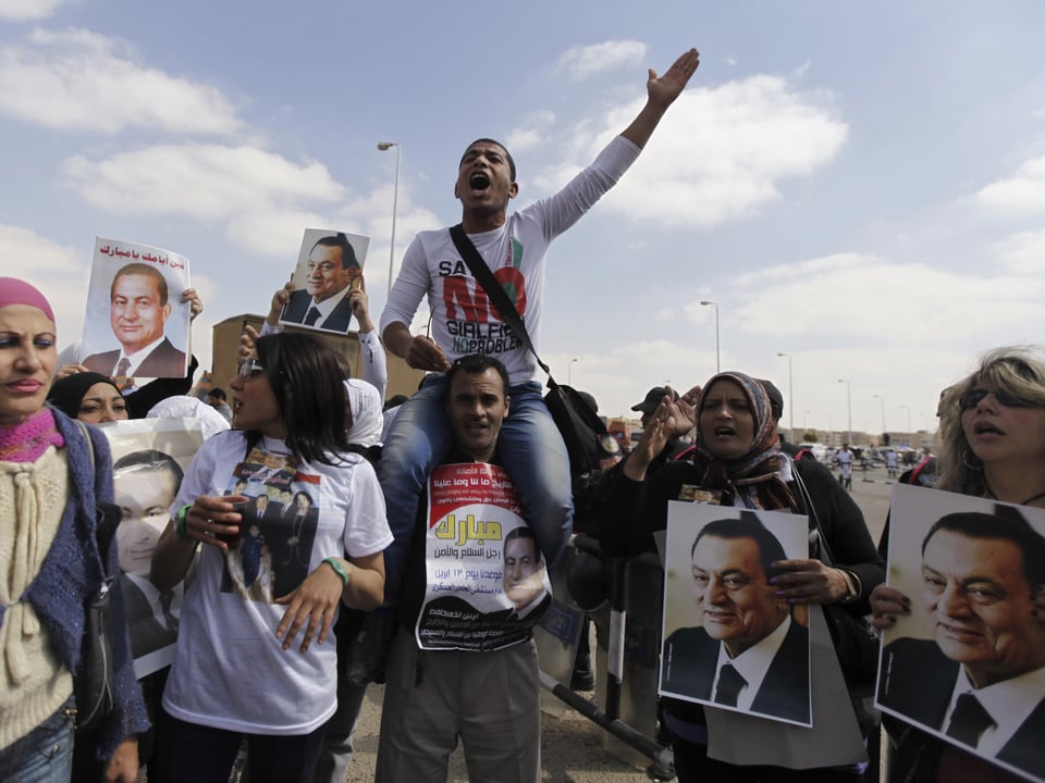 Pro-Mubarak-Demonstranten halten Porträts des Ex-Präsidenten und fordern seine Freilassung.