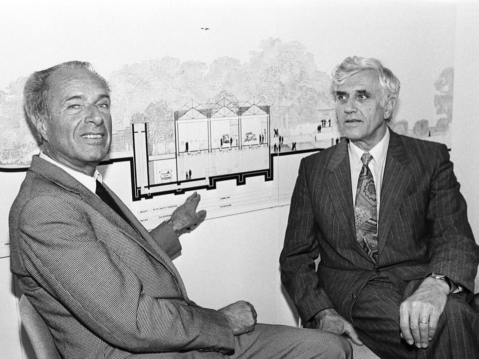 Schwarz-Weiss Foto zweier Herren vor einem Architektur-Plan