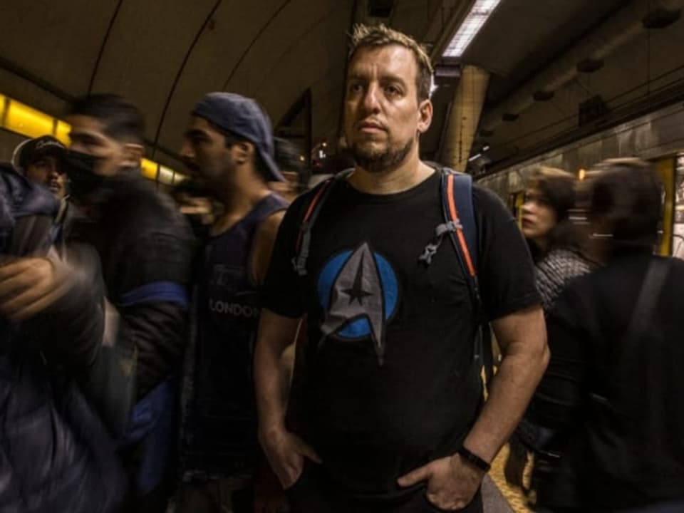 Ein Mann steht mitten im Strom von Menschen in der U-Bahn-Station.