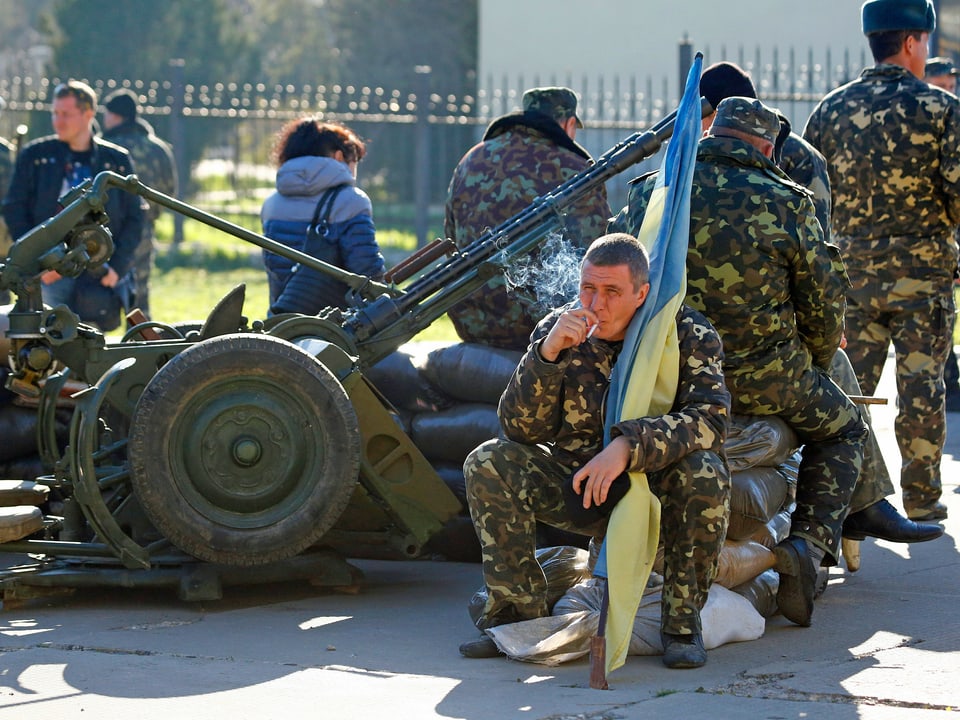 Soldat sitzt auf Geschütz.