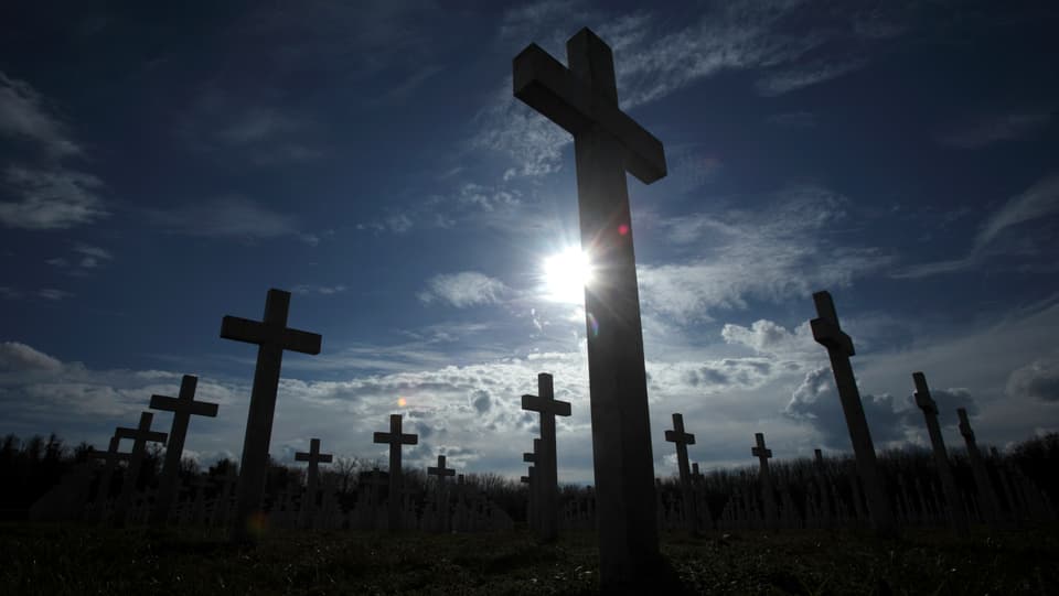 Kreuze zur Erinnerung an Kriegsopfer stehen auf einem Feld.