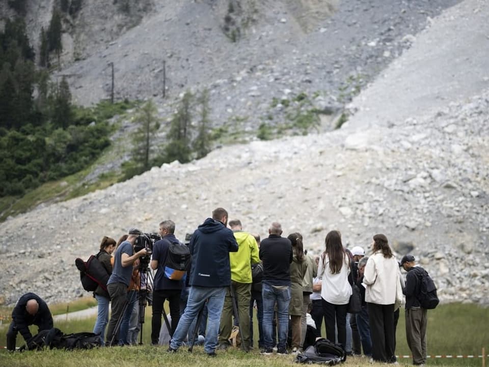 Mehrere Menschen vor Steinschutt am Hang eines Berges.