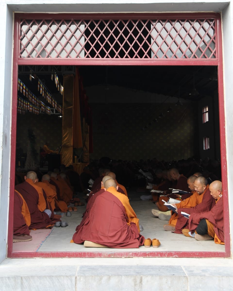 Mönche sitzen in einem Raum uns lesen.