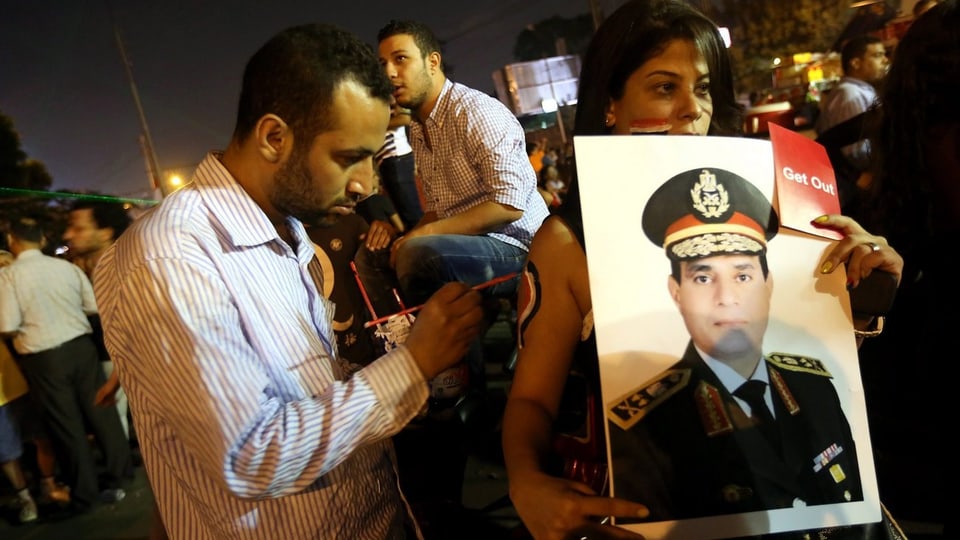 Protestierende halten ein Plakat von Abdel Fattah al-Sisi hoch.