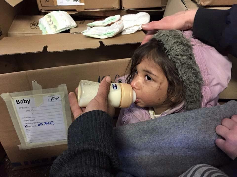 Kleines Mädchen trinkt aus einem Milchfläschen