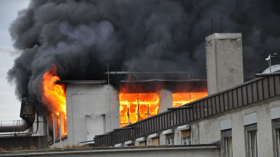Flammen schlagen aus einem Obergeschoss der Fabrikhallen.