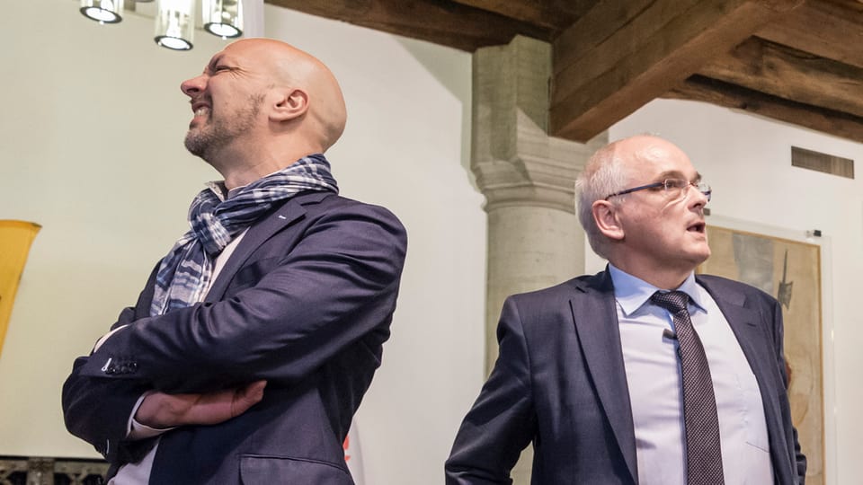 Zwei Männer stehen mit dem Rücken gegeneinander.