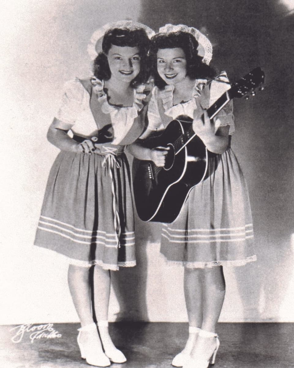 Schwarzweissfoto: zwei junge Frauen in Röcken und mit Cowboy-Hüten.