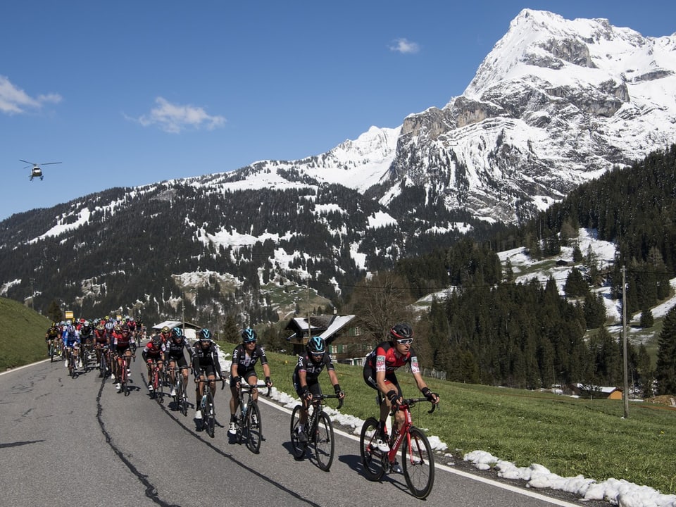 Radrennen mit Gruppe von Radfahrern auf einer Strasse in den verschneiten Bergen.