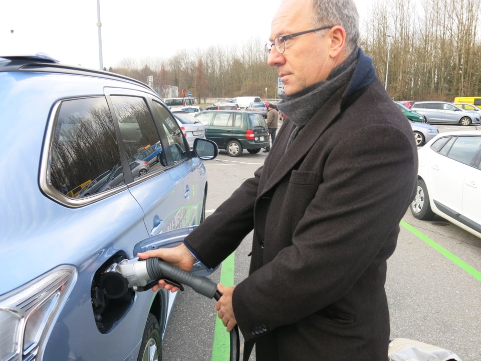 Urban Achermann, der Marketing-Direktor von Groupe E, lädt ein Hybridauto mit Strom auf.