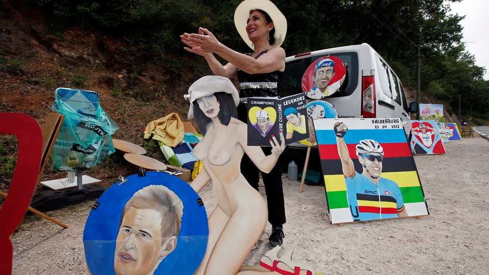 Radsport-Anhängerin und Künstlerin am Strassenrand mit Bildern.