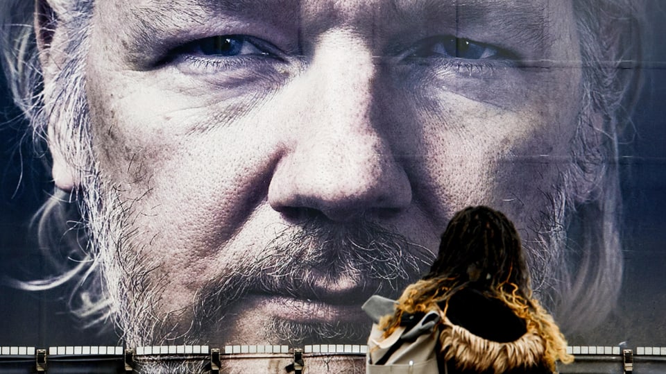 Frau steht vor Bild von Julian Assange
