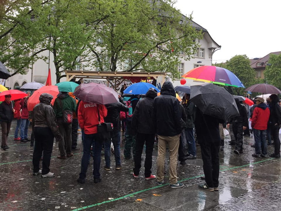 Eine Gruppe Menschen steht vor dem Amtshaus auf dem Zürcher Helvetiaplatz, um einer 1. Mai-Rede zuzuhören. 