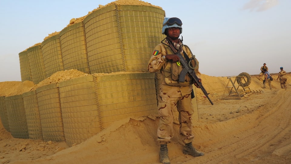 Schwarzer Blauhelm-Soldat steht im Wüstensand Wache bei einem UNO-Stützpunkt in Mali, Archivbild vom Juli