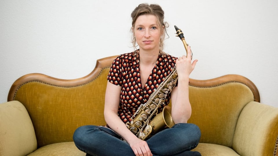 Frau mit Saxofon auf einem Sofa.