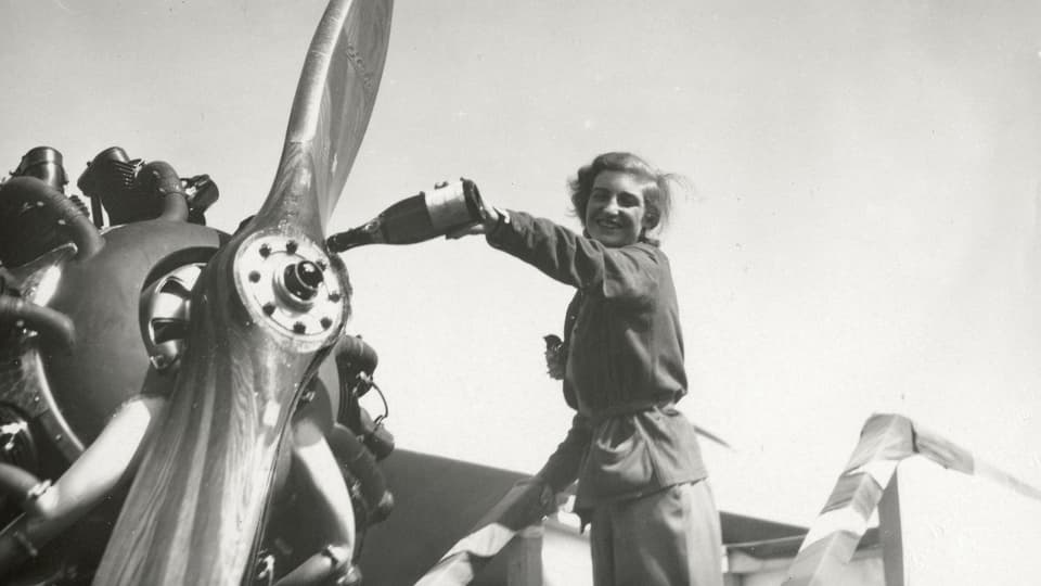 Margaret Fusbahn leert eine Flasche Sekt über den Propeller eines Flugzeuges.