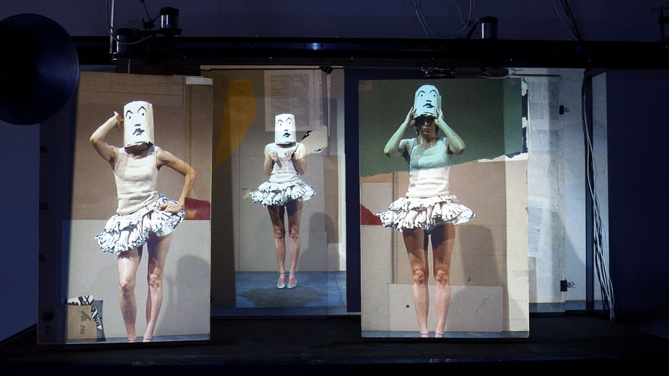 Drei Projektionen zeigen eine Frau im Ballettrock. Ihr Geischt ist bedeckt.