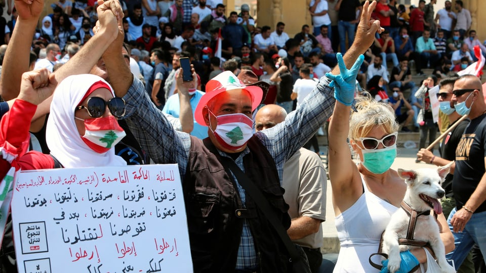 Demonstrantinnen und Demonstranten mit Transparent, manche tragen eine Gesichtsmaske.