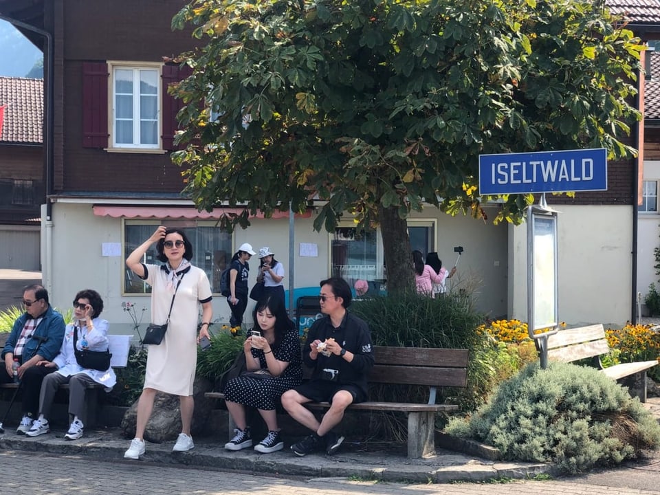 Koreanische Touristen sitzen auf Parkbänken