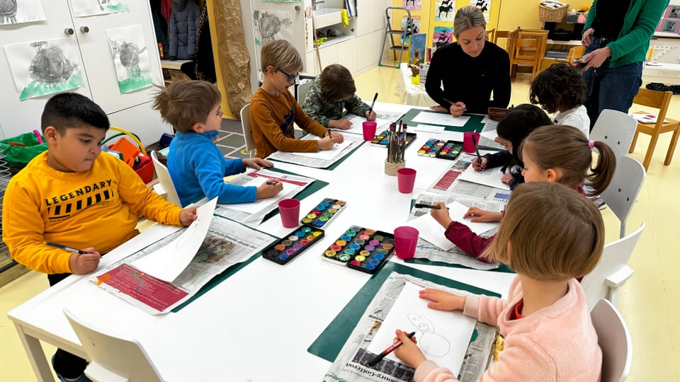 Kinder und Erwachsene beim Kunstunterricht in einem Klassenzimmer.
