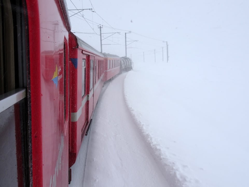 Die roten Bahnwagon des Räthischen Bahn leuchten in der weissen Winterlandschaft.
