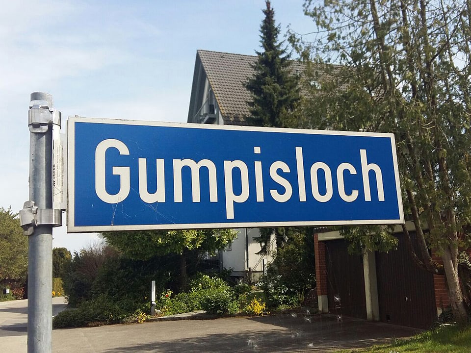 Auf einem Strassenschild steht Gumpisloch.