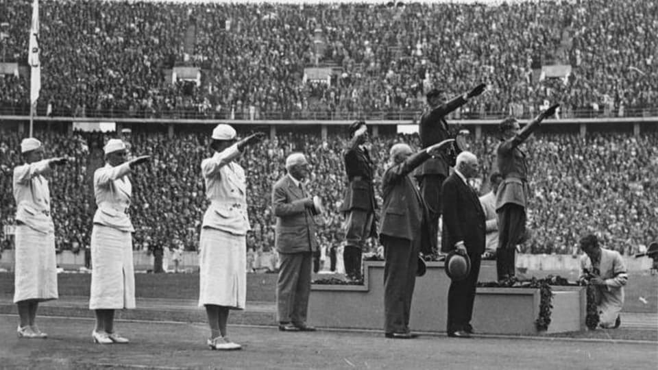 Schwarzweiss-Bild einer Siegerehrung, mehrere Menschen zeigen den Hitlergruss.