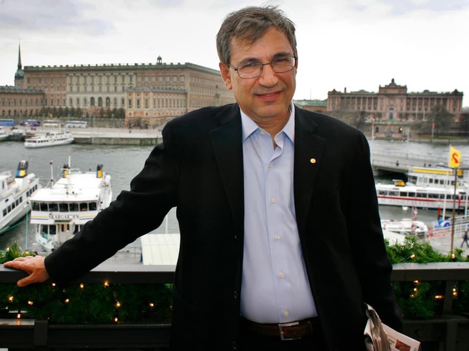 Orhan Pamuk auf einem Balkon, hinter ihm der Blick auf Stockholms Altstadt