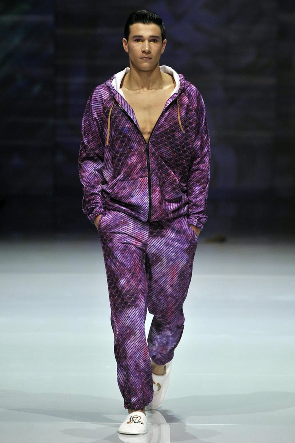 männliches Model auf Laufsteg mit vioeltten Kleider