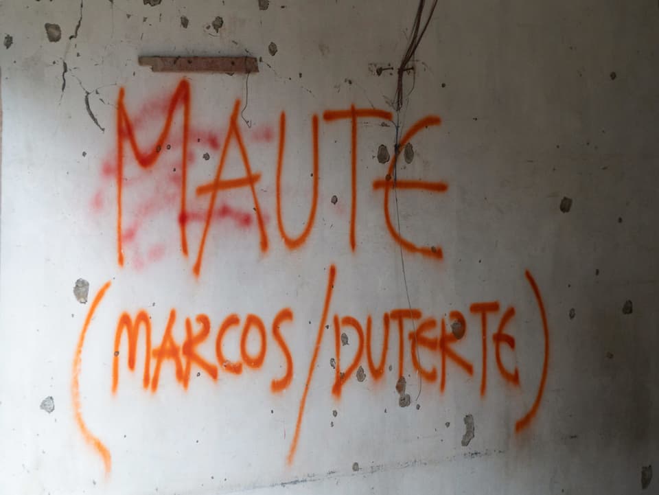 Graffiti an einer Wand mit Einschusslöchern: MAUTE (MARCOS / DUTERTE)
